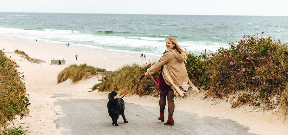 Finja geht mit einem schwaren Hund an den Strand