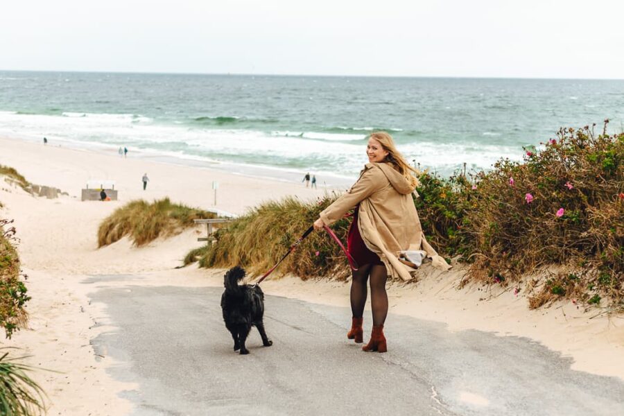 Finja geht mit einem schwaren Hund an den Strand